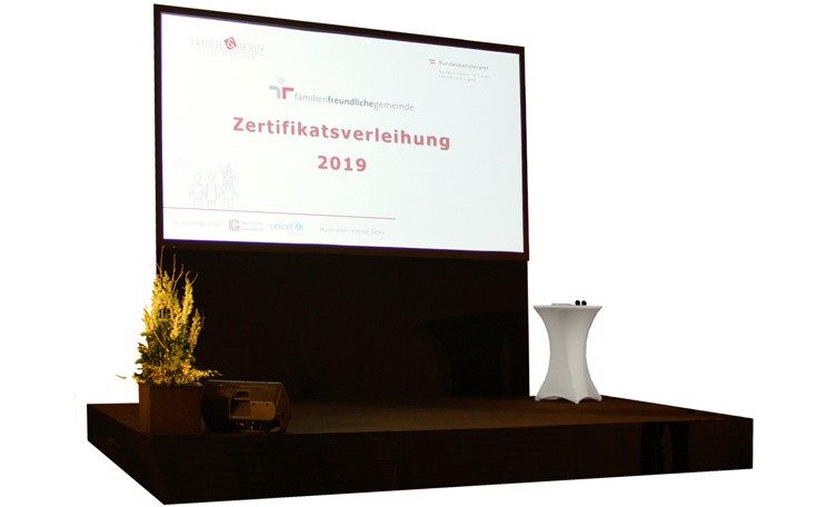 Bühne mit schwarzem Teppich und dahinter einer Leinwand und Konferenztechnik in Wien